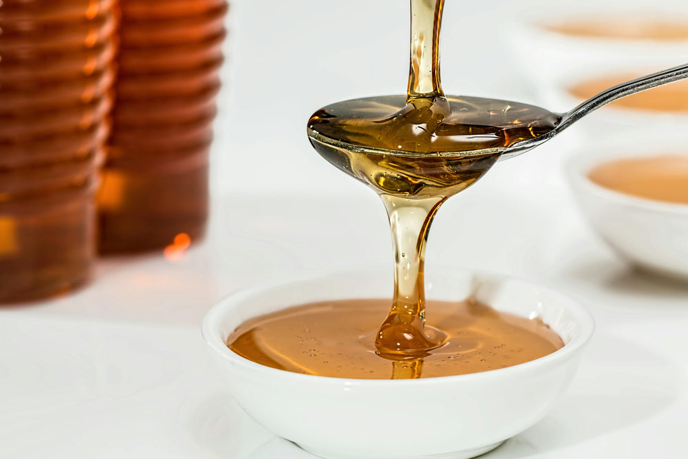 raw honey in spoon to make oatmeal honey shea butter soap