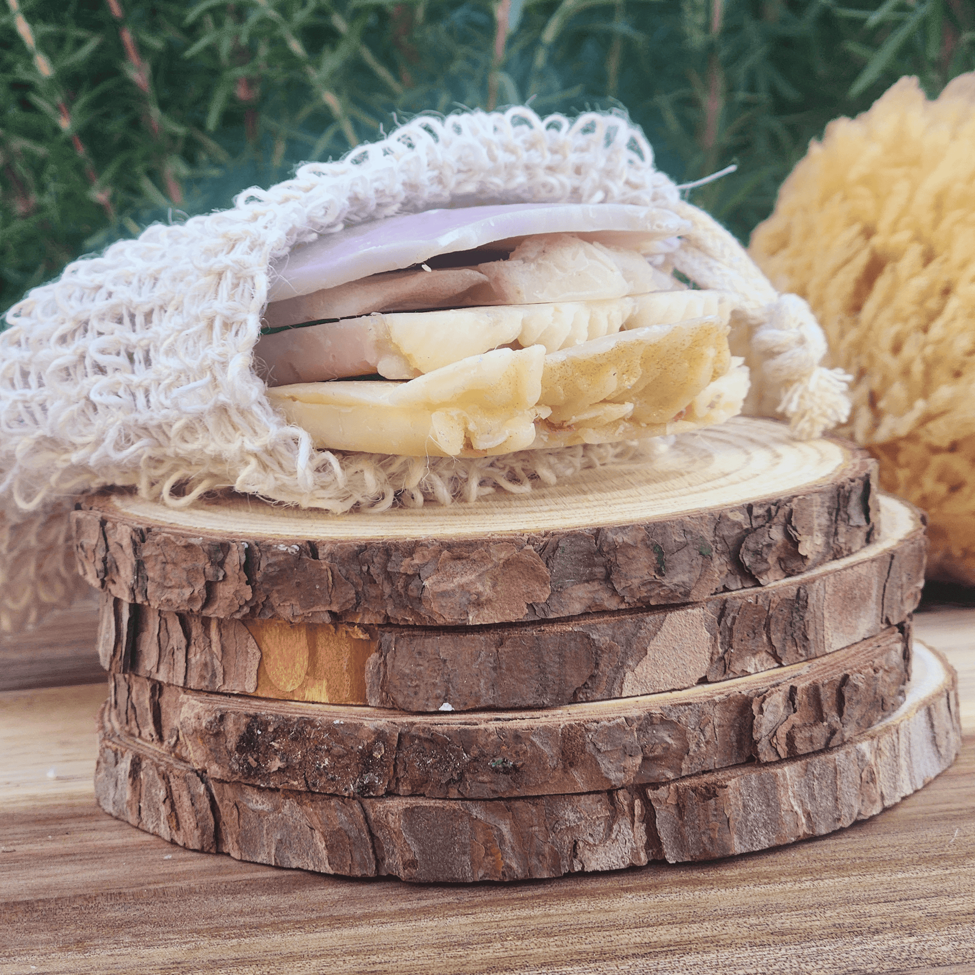 Handmade soap samples and sisal bag with natural soap bars displayed on wooden slices